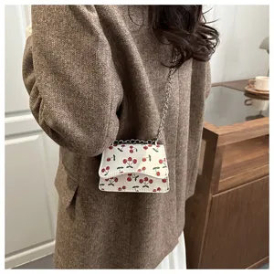 Detailansicht der Mini-Umhängetasche mit Kirschmuster und Silberkette am Model