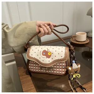 Detail of cute checkered crossbody bag with red polka dots and brown bear plush charm