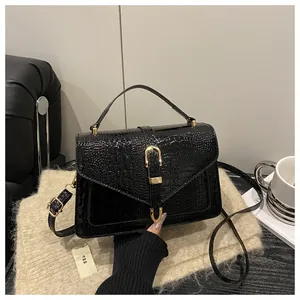 Close-up of black crocodile embossed patent leather handbag with golden hardware