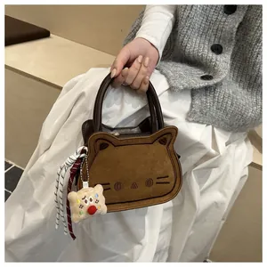 Detail of cute embroidered cat-shaped brown suede handbag with plush charm and braided cord