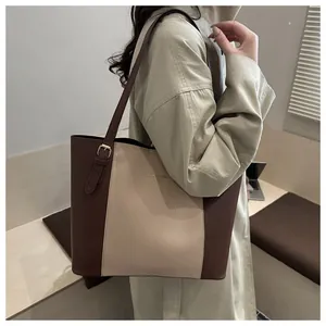 Detail of adjustable strap and gold logo on contrast color leather tote bag