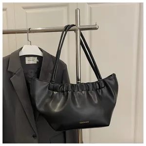 Detail of black pleated faux leather shoulder bag with gold Fashion Bags lettering