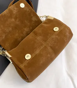 Detail van bruine matte schoudertas met gouden magnetische gesp en fijne stiksels