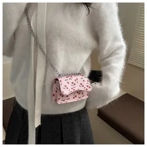 Nahaufnahme der rosa Mini-Umhängetasche mit Kirschmuster und Silberkette am Model