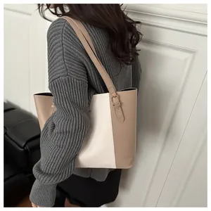 Detailed back view of a minimalist beige leather tote bag worn by a model in a room