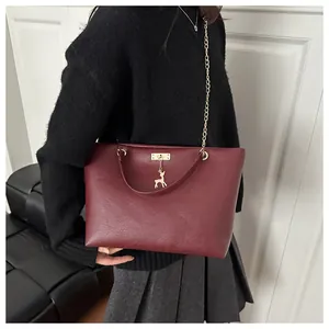 Detail of burgundy tote bag with gold chain strap and elegant deer pendant