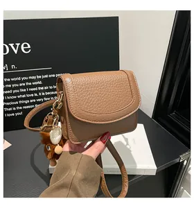 Detail of brown pebbled leather crossbody bag with cute plush animal charm accessory