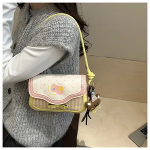 Detail of pink plaid bag with cream polka dot flap and cute teddy bear pendant
