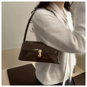 Close-up of a glossy dark brown baguette bag featuring a gold U-shaped metal buckle