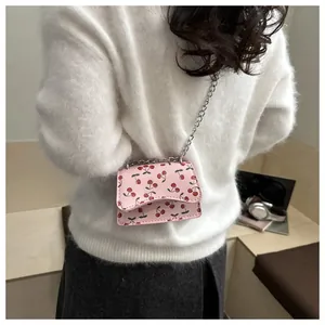 Detailansicht der rosa Umhängetasche mit Kirschmuster und Silberkette auf weißem Pulli