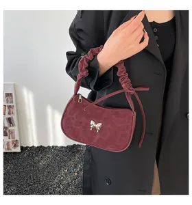 Detail of silver butterfly buckle on wine red faux suede underarm bag with leopard print