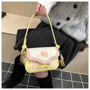 Close-up of pink apple small square bag with yellow bow and plush bear charm detail