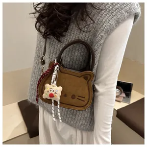 Detailed close-up of brown cat-shaped suede handbag featuring cute embroidery and charms
