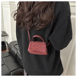 Mini brick red crossbody bag shown on a black sweater to demonstrate its compact size