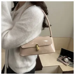 Detail of a chic apricot baguette bag featuring a shiny finish and gold metal twist lock