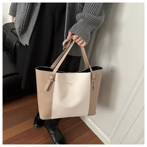 Detail of a large color-block tote bag with gold logo and adjustable strap buckles