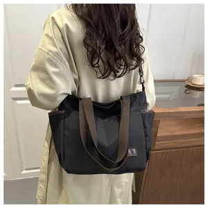 Détail du grand sac cabas noir avec anses brunes montrant la poche latérale et l'étiquette
