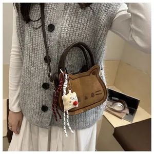 Detail of cute cat-shaped crossbody bag with soft matte texture and plush bear charm