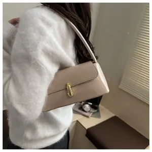 Detailed side view of a beige patent leather baguette bag with gold buckle on a model