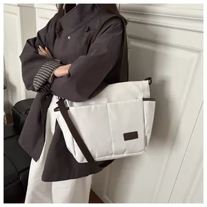 Grand sac fourre-tout en toile blanche avec bandoulière marron porté par un mannequin chic