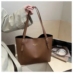 Detail of adjustable strap with metal buckle on large brown faux leather tote bag