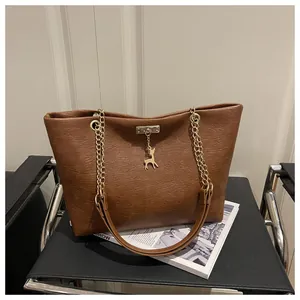 Close-up of brown faux leather tote bag with gold chain strap and deer pendant