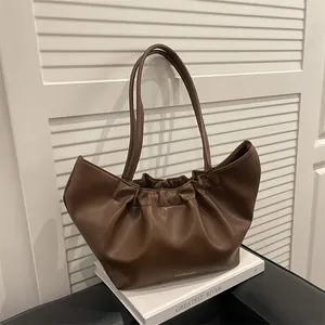 Brown soft leather tote bag with cloud pleats and gold lettering on white decor