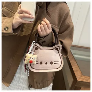 Detail of sweet pink cat shaped handbag with brown embroidery and plush pendant charm