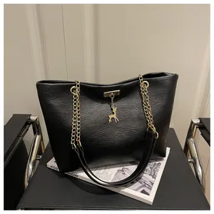 Detail of matte black tote bag with gold deer charm and metallic chain strap