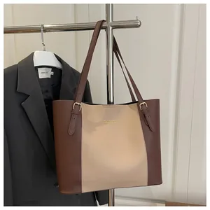 Detail of adjustable metal buckle and contrast stitching on two-tone tote bag