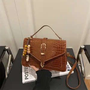 Chic brown crocodile embossed square handbag with metallic clasp and beaded charm