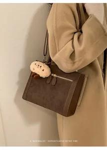 Detalle de bolso tote retro de ante tipo patchwork con cremallera dorada y colgante
