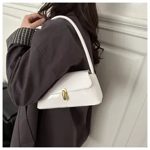 Detail view of white patent leather baguette bag with elegant golden metal clasp on strap