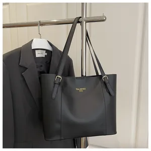Detail view of black leather tote bag featuring gold hardware and logo for work commute