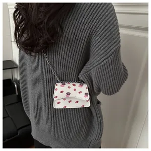 Detailansicht der weißen Mini-Umhängetasche mit Lippenmuster und silberner Kette