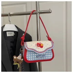Detail of pink apple handbag with blue polka dots and a cute teddy bear charm hanging