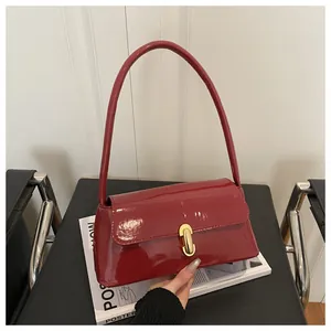Detailed view of red glossy patent leather baguette bag with a golden twist lock