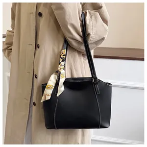 Détail du cabas noir avec surpiqûres contrastées et foulard en soie sur la poignée