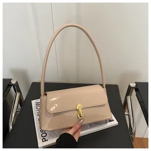 Close-up of beige patent leather baguette bag with shiny gold cylindrical metal lock