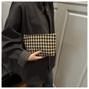 Detail of checkered woven makeup bag with black and white rhombus patterns and top zipper