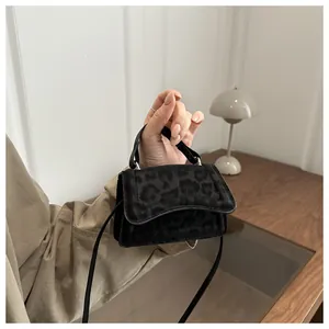Close-up of black leopard print mini handbag with thin strap and top handle design
