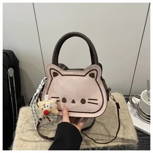 Close-up of cute cat face embroidery on matte pink crossbody bag with brown handle