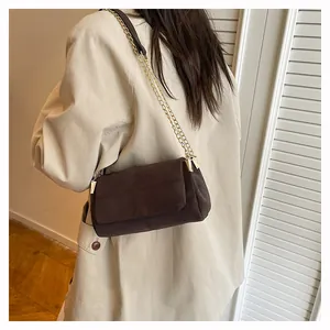 Détail du sac bandoulière marron foncé mat avec coutures en croix et chaîne dorée