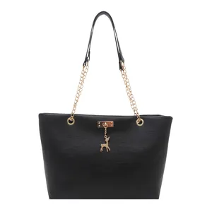 Large black matte tote bag with gold chain strap and deer pendant on white background