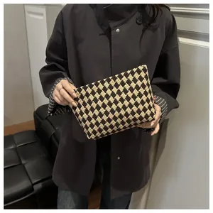 Close-up of checkerboard knit toiletry bag held by model in a minimalist setting