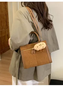Bolso tote retro de ante marrón con correas largas y un colgante de peluche blanco