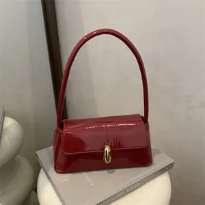 Retro red patent leather baguette bag with golden buckle shown in a lifestyle setup