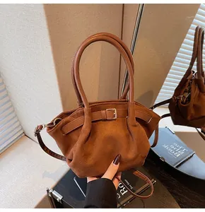 Detailweergave van bruine suède handtas met decoratieve gesp en spiegelreflectie