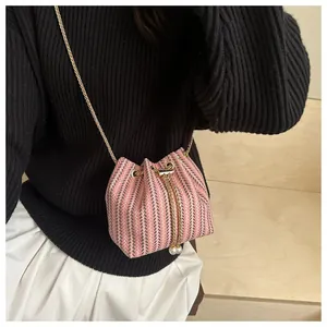 Détail du sac seau à rayures roses et blanches avec perles et bandoulière dorée