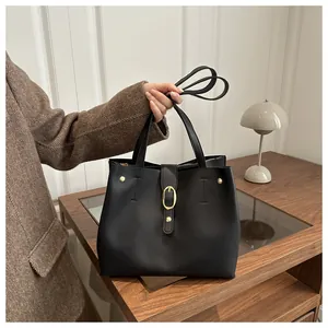 Detail of a vintage black tote bag with gold metal buckle and adjustable shoulder strap
